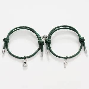 Close-up detail of green rope couple magnetic bracelets with metal lock and key charms display.