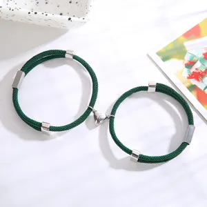 Groene gevlochten koppel armbanden met magnetische hartsluiting en zilveren metalen buizen detail.