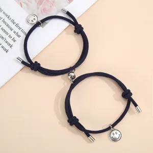 Detailed shot of handmade woven rope couple bracelets with magnetic attraction and smiley charms.
