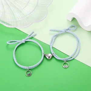 Close-up detail van paar magnetische bijpassende gevlochten touw armbanden met hart.