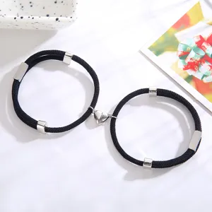 Set van bijpassende gevlochten touw armbanden met magnetisch hart en zilveren metalen buizen.