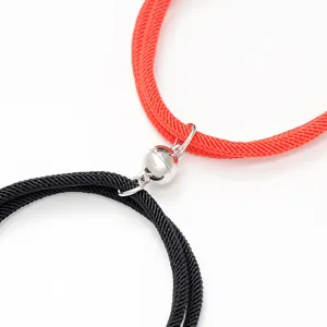 Close-up detail of red and black couple magnetic braided bracelets connecting clasp.