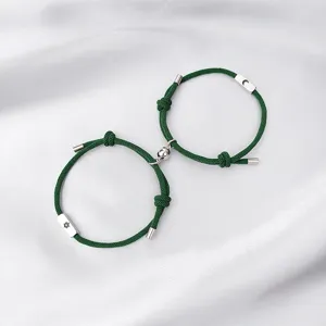 Detailed view of the magnetic sun and moon couple bracelets with green braided ropes.