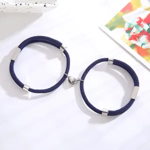 Close-up detail van magnetisch hart koppel gevlochten touw armband op witte achtergrond