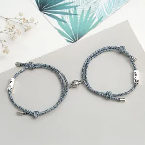 Set di bracciali di coppia intrecciati blu con chiusura magnetica e ciondoli in metallo.
