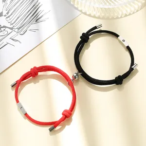 Detailed view of magnetic sun and moon couple bracelets featuring black and red woven rope.