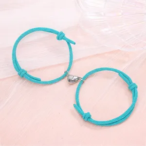 Close-up detail of the cyan braided couple bracelets featuring a magnetic heart charm component.