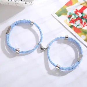 Detailopname van magnetische hartje koppelarmbanden met blauw gevlochten touw en zilveren buisjes.