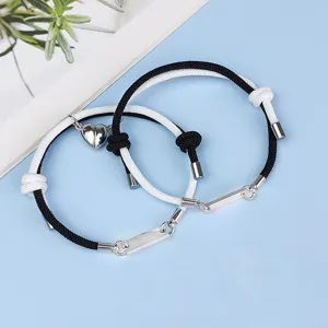 Close-up detail of magnetic couple heart bracelet, black white woven rope, stainless steel bar.