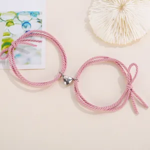 Close-up detail of couple magnetic heart braided rope bracelet in pink fashion style.