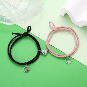 Gedetailleerd weergave van koppel magnetische armbanden met hart en golf bedels zwart roze.