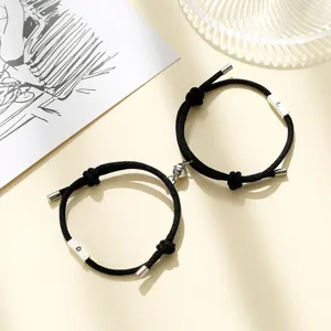Detailed view of black braided cord couple bracelets featuring magnetic sun and moon charms.