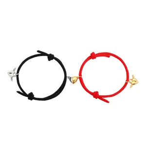 Close-up detail of magnetic couple bracelets with heart charms and braided ropes.