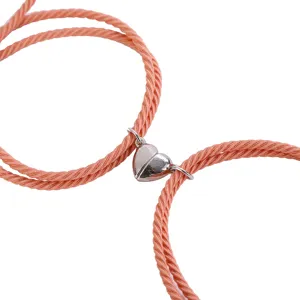 Detail shot of magnetic heart couple bracelets with pink braided cord and silver clasp.