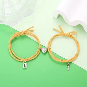 Gedetailleerd overzicht van stijlvolle koppelarmbanden van geel gevlochten touw met hart.