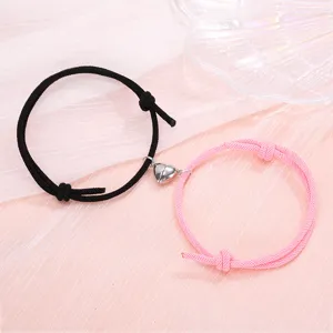Close-up of magnetic couple heart bracelets with black and pink woven rope design details.