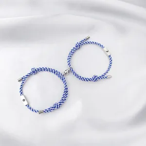Detailed view of blue and white braided couple bracelets with magnetic sun and moon charms.