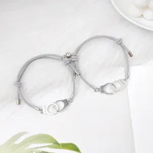 Vue détaillée de bracelets de couple magnétiques menottes tissés gris, design élégant.