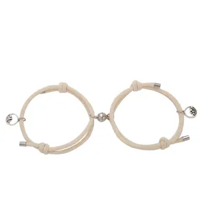 Set di bracciali di coppia magnetici in corda beige con ciondoli in lega e punte metalliche.