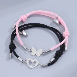 Pulsera trenzada de pareja con corazón magnético y dijes de mariposa en negro y rosa.