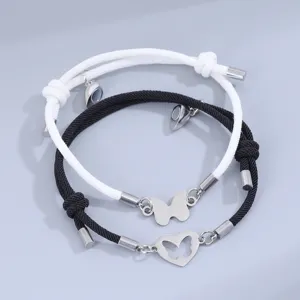Detalle en primer plano de pulseras de pareja trenzadas en blanco y negro con dijes magnéticos.