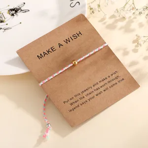 Detailed close-up view of a colorful braided cotton cord wish bracelet with a gold bead on card.