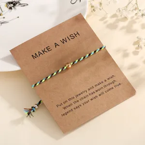 Minimalist braided cotton rope wish bracelet with metal bead on kraft paper display card.