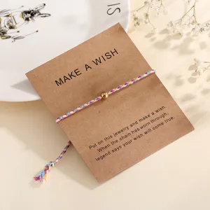 Colorful braided wish bracelet with golden bead on craft paper card, adjustable string.
