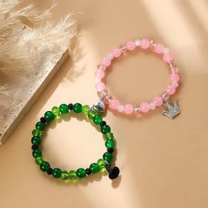 Wicked thematisierte Paar-Magnet-Perlenarmbänder mit grünem Hexenhut und rosa Kronenanhängern.