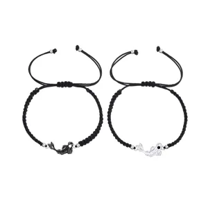 Primer plano detallado del conjunto de pulseras de pareja trenzadas con dijes de pez.