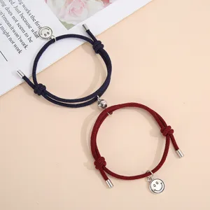 Close up detail of handmade woven couple magnetic attraction smiley face bracelets in dark blue and red.