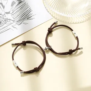 Close-up of brown braided couple bracelets with sun and moon charms and magnetic clasp detail.