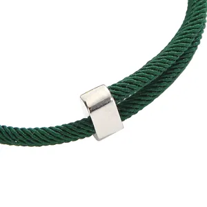Gedetailleerd weergave van een stijlvolle groene gevlochten koord armband met metaal.