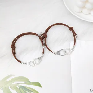 Détail de bracelet cordon tressé magnétique couple, menottes en alliage et bijou marron.