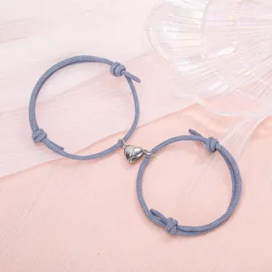Close up detail of couple magnetic heart bracelet featuring blue woven cord and alloy charm.