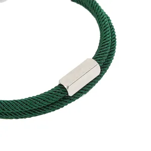 Detailopname van de groene gevlochten koordarmband met een slanke zilveren metalen sluiting.