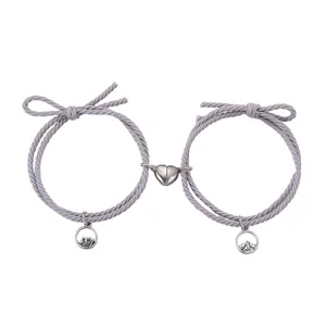 Koppel magnetische bijpassende armbanden met berg- en oceaanbedels en grijs touw.