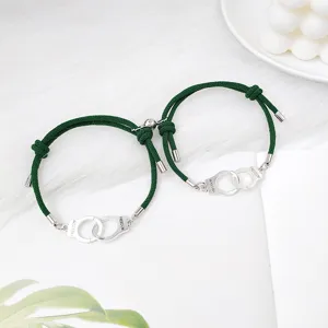 Gros plan détaillé de bracelets de couple tressés verts avec pendentifs menottes en argent.