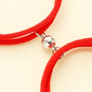 Close-up detail of red braided couple bracelets with a silver magnetic attraction spherical clasp.