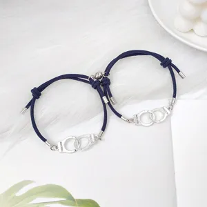 Gros plan de bracelets de couple magnétiques menottes en alliage minimalistes avec cordon bleu.