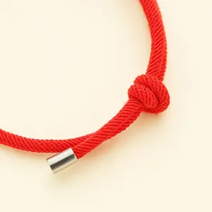 Detail close-up shot of red woven friendship bracelet cord with metal tip and knot detail