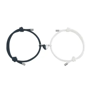 Close-up of black and white rope couple bracelets with magnetic connecting half-heart charms.