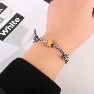 Black and white woven rope bracelet with gold metal bead detail, minimalist style jewelry.