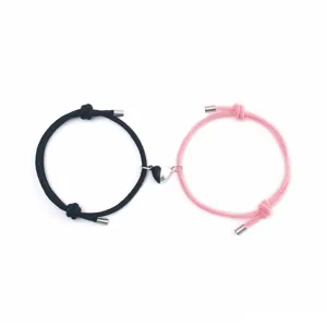 Detailed shot of couple magnetic braided bracelets with black and pink matching heart pendants.