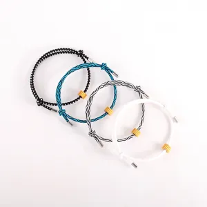 Detailed view of woven survival cord bracelets featuring metallic gear charms and adjustable locks.