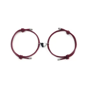 Close-up detail of matching couple magnetic heart woven bracelets in dark red color.