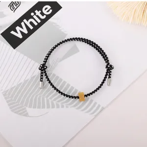 Black and white braided rope bracelet detail showing metal bead and unique design.