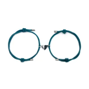 Close-up detail of couple magnetic heart bracelet set with dark teal woven rope and half black silver charm.