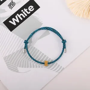 Close-up of blue and black braided rope bracelet with metal charm and tips for daily wear.