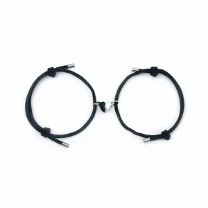Detailed view of black woven rope couple bracelets featuring a connected magnetic heart charm.